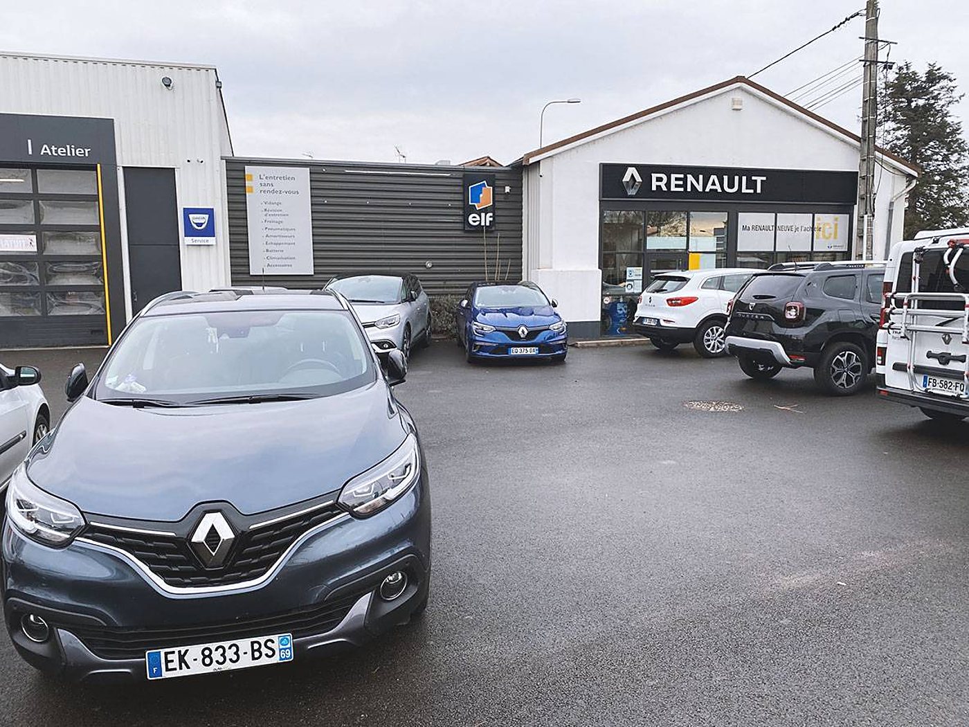 Façade d'un garage Renault et de son atelier Dacia, avec plusieurs voitures stationnées sur le parking en premier plan.