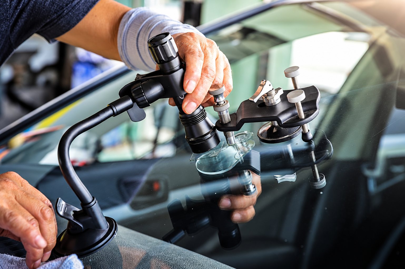 Un technicien utilise un injecteur de résine fixé par ventouse pour réparer un impact sur le pare-brise d'un véhicule.