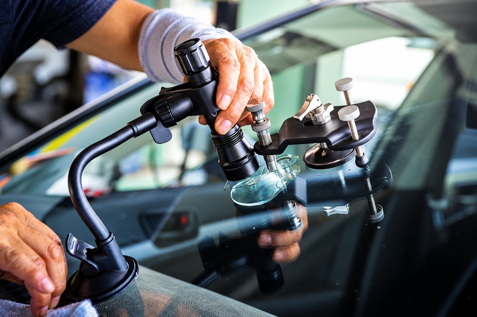 Un technicien utilise un injecteur de résine fixé par ventouse sur un pare-brise pour réparer un impact.